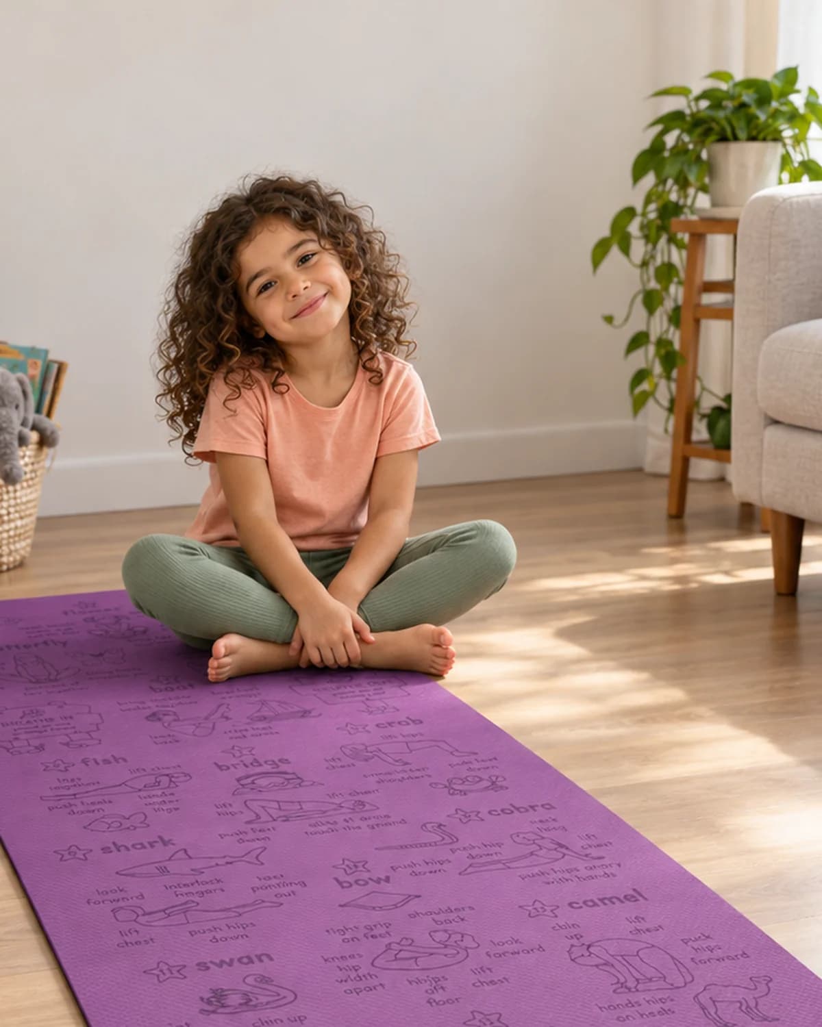 A child sitting cross-legged and smiling on a purple Yogi-Me mat in a sunlit living room