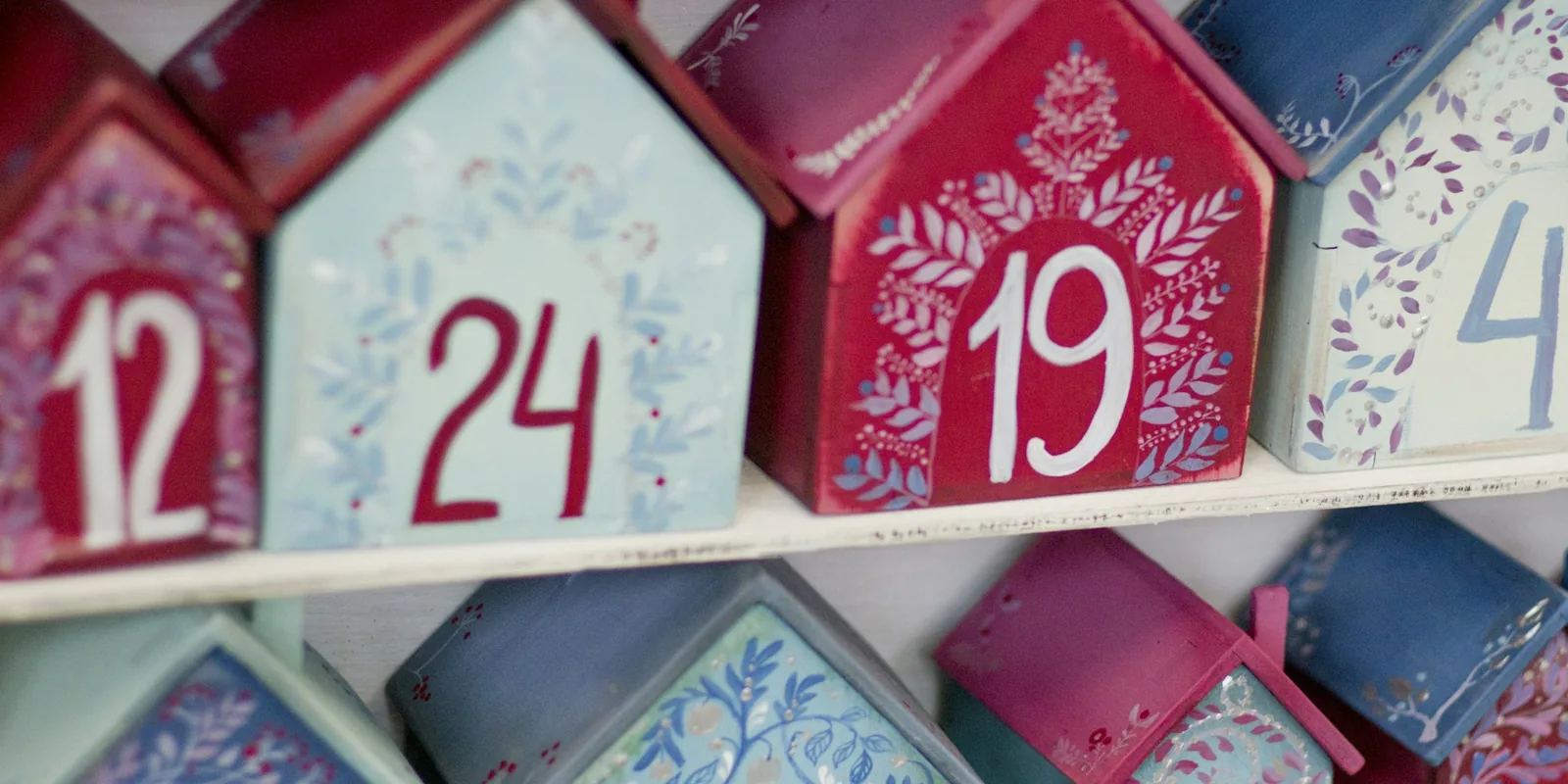 Close-up of a wooden advent calendar made of small painted houses, each with a number on the front