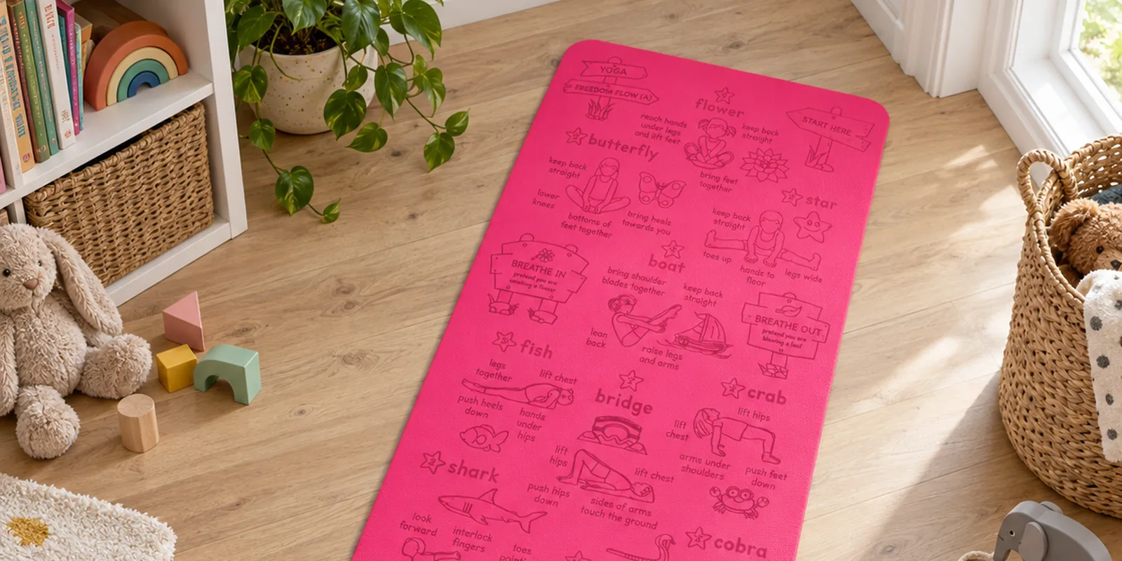 A pink Yogi-Me Freedom Flow kids' yoga mat on a playroom floor, engraved poses including butterfly, boat and bridge, a toy rabbit beside it