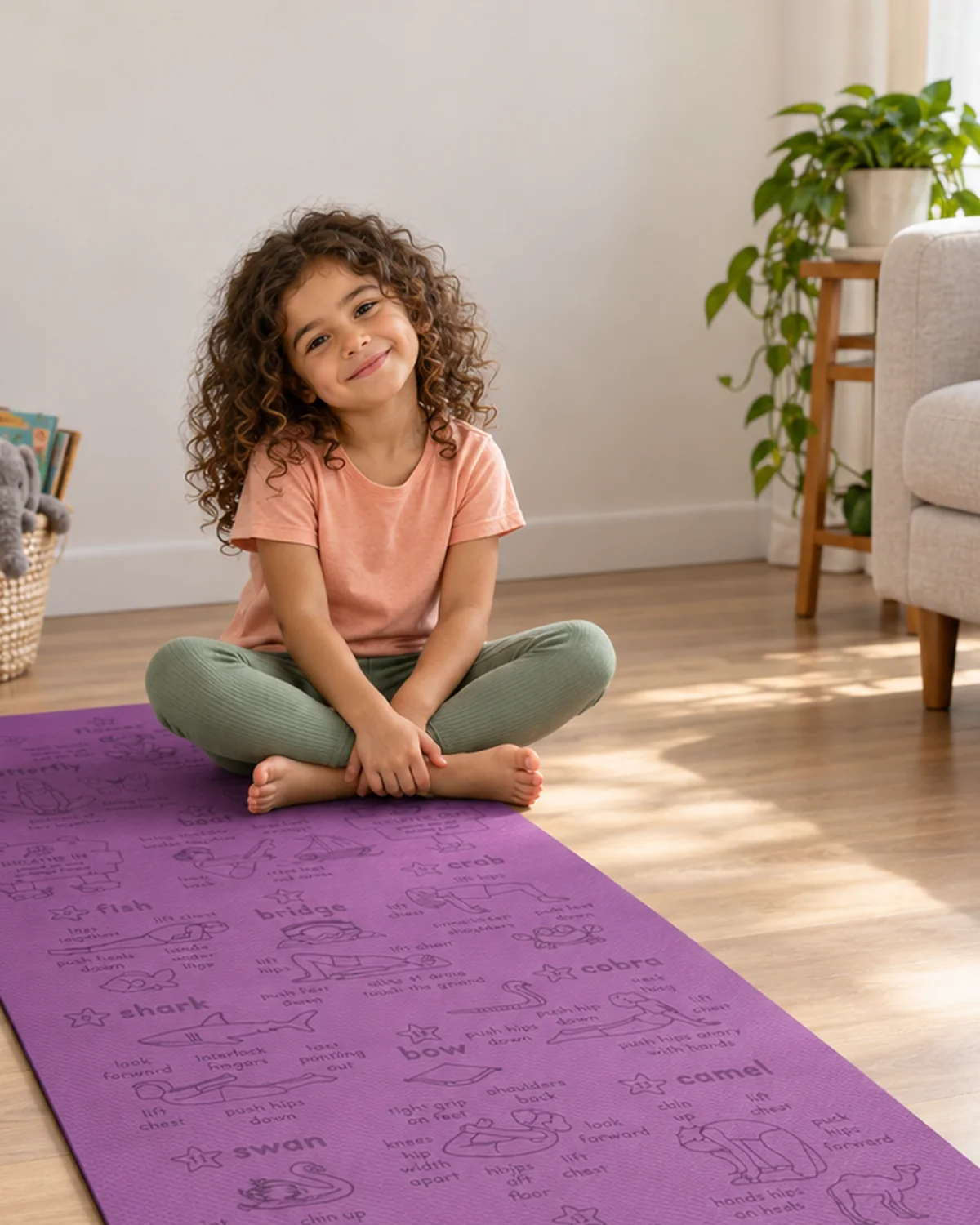 A child sitting cross-legged and smiling on a purple Yogi-Me mat in a sunlit living room